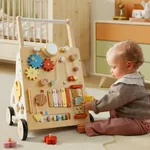 Baby sitting on floor playing with garden themed wooden activity walker panel