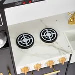 Close-up top view of marble pattern stovetop burners and gold knobs on wooden play kitchen