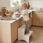Child standing on wooden 2 step stool helping at kitchen counter