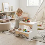 Toddler sitting near wooden 2 step stool playing with wooden blocks on top